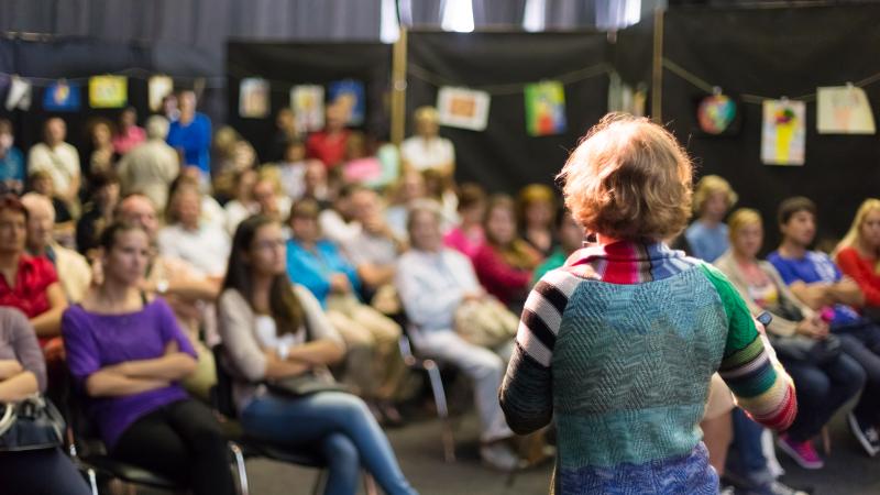 Woman stands in front of an audience.